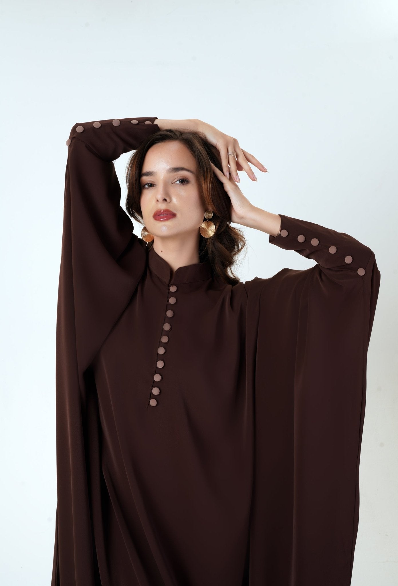 velvet road abaya- Woman wearing beautiful brown batwing abaya with contrast buttons. Elegant fashion by MODMOD UK. 